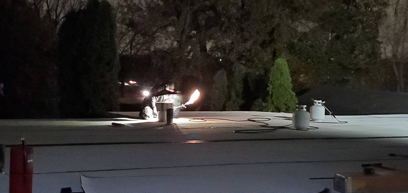 Ryan working around a roof vent on a flat roof at night