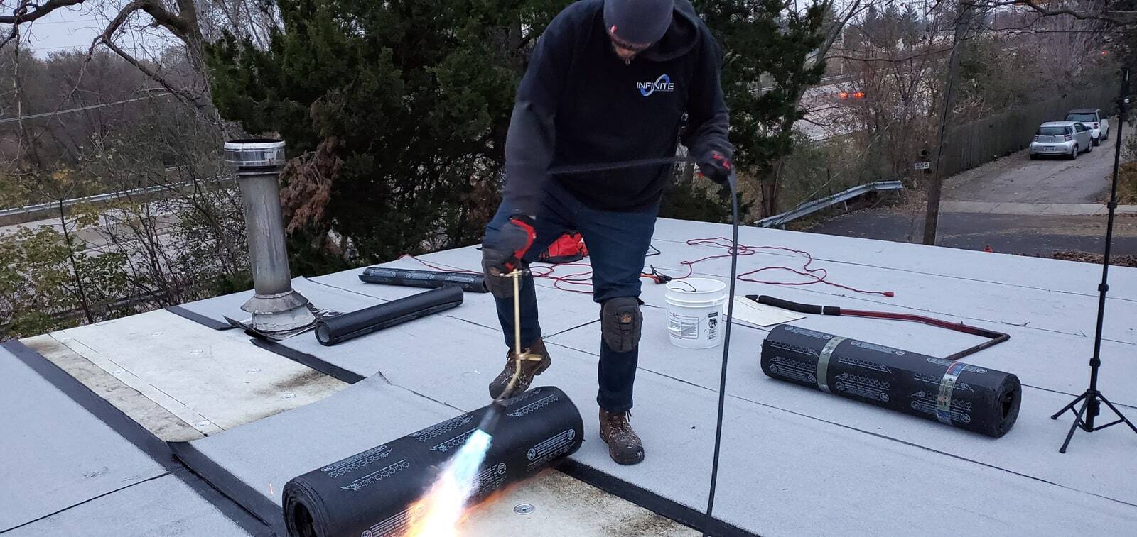 Ryan using a roofing torch beside a roll of roofing membrane